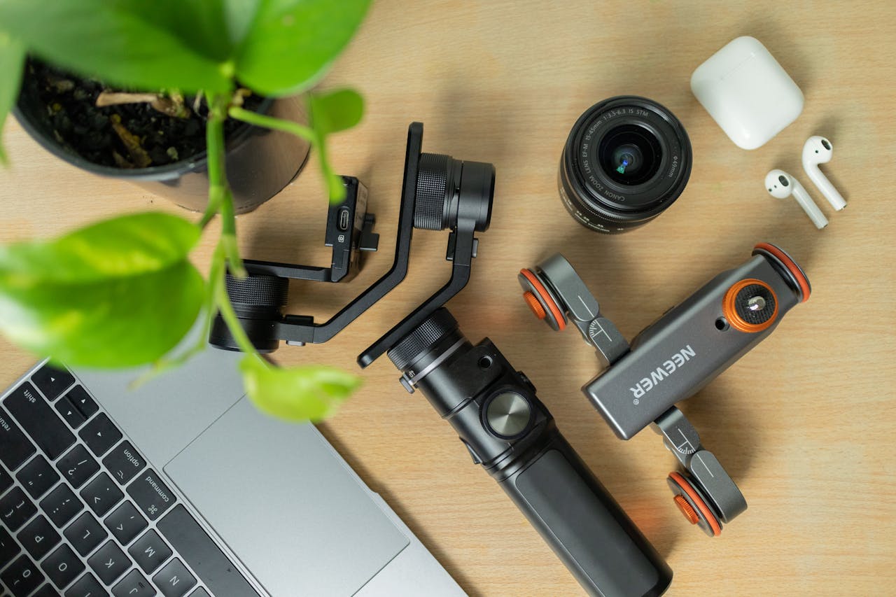 Flat lay of camera gear and tech devices on a wooden table, perfect for photography enthusiasts.