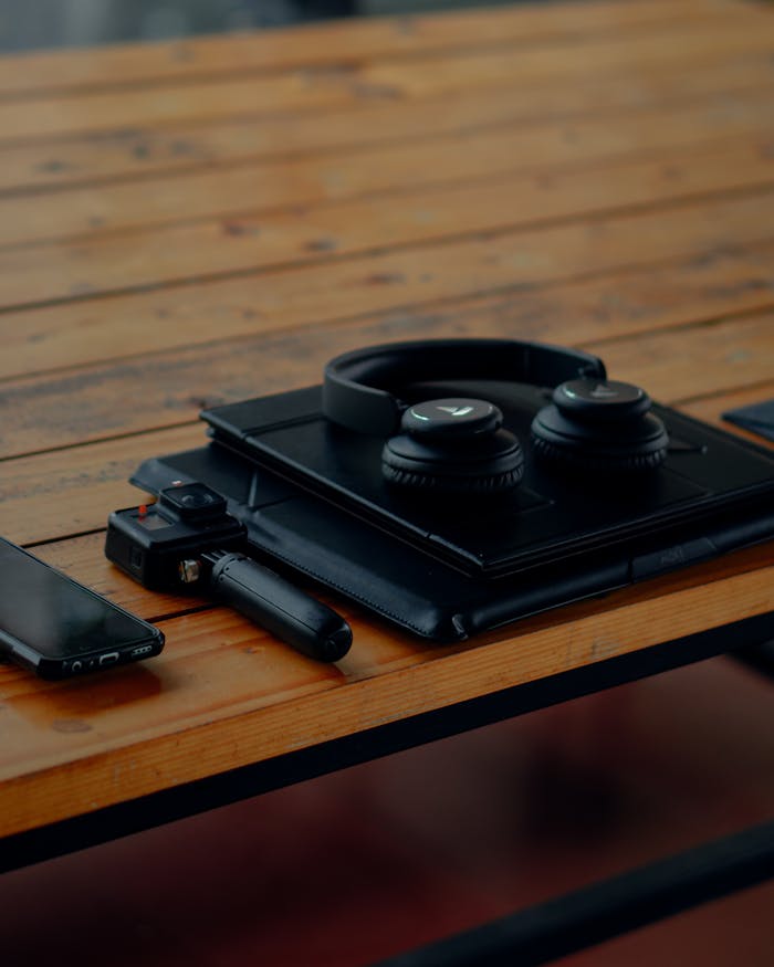 Close-up shot of gadgets including headphones, smartphone, and GoPro on a wooden table.